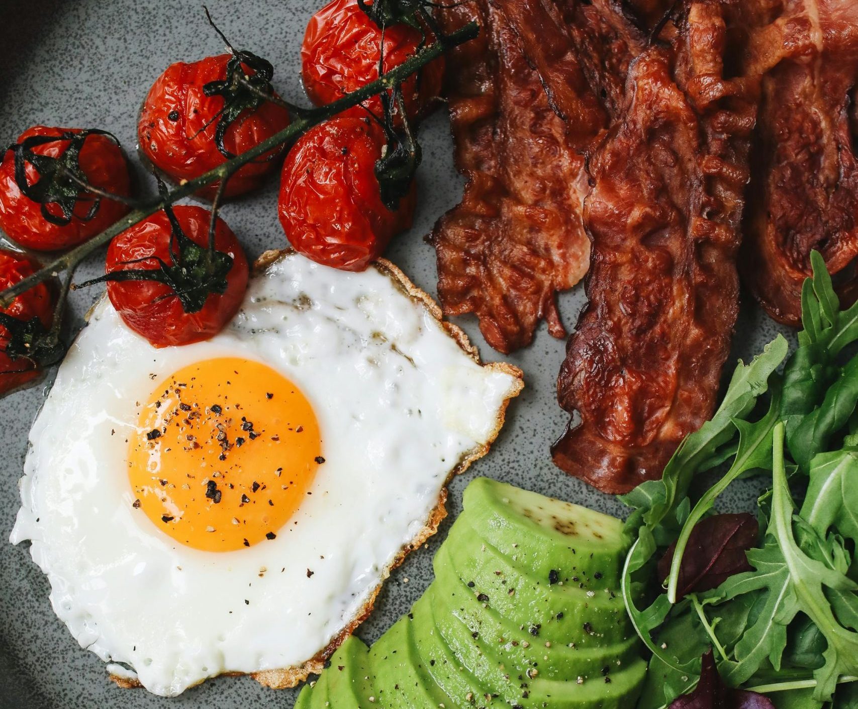 Plato de comida keto con proteína a la plancha, aguacate y verduras verdes salteadas, ideal para dieta cetogénica rica en grasas saludables y baja en carbohidratos.